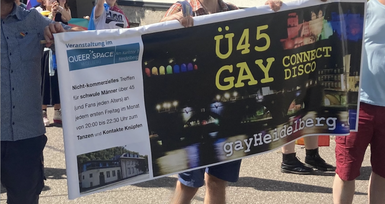 Christopher Street Day Eine Gruppe von Menschen hält ein Banner mit der Aufschrift "Ü45 GAY" und bunten Lichtern. CSD Gay Pride. Christopher Street Day March.